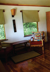 Luxury accommodation bedroom with open bedroom windows, study table, and chair at Lion Sands Masai Mara