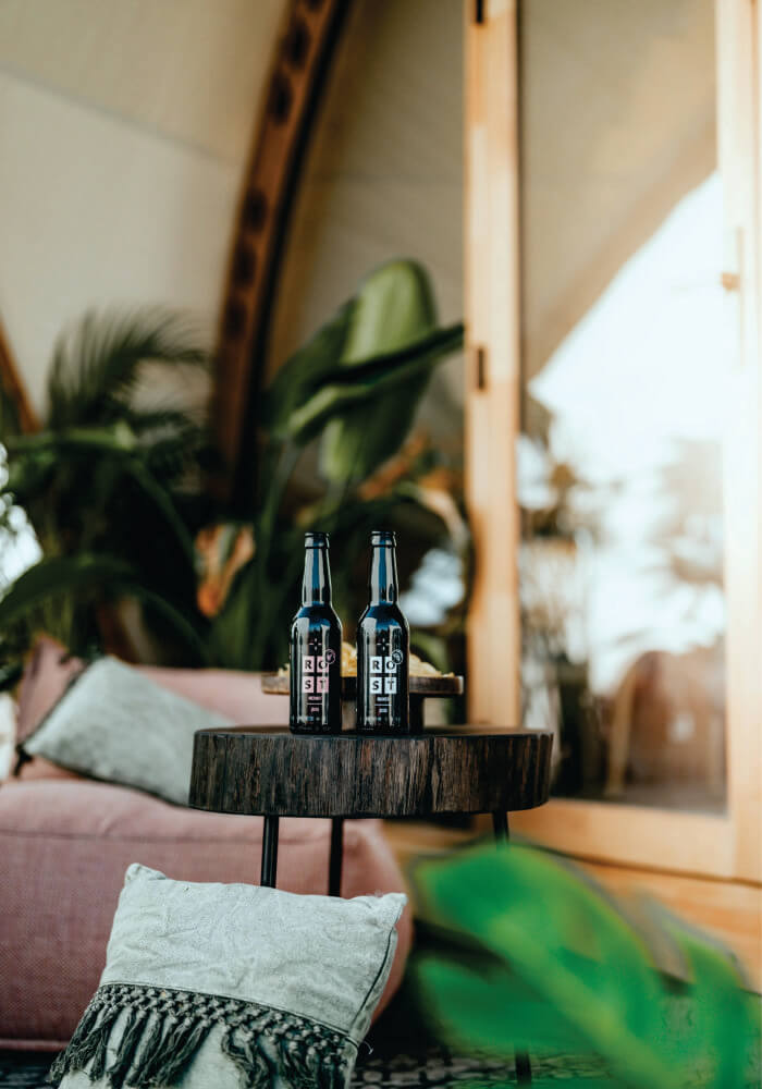 Two black alcohol bottles on a wooden table at Lion Sands Lodge for enjoying a refreshing beverage with mesmerizing views of nature on affordable Masai Mara Safari 3 Days.